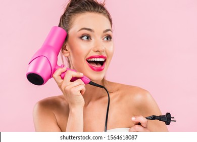 Excited Beautiful Woman With Open Mouth And Pink Lips Holding Hairdryer Isolated On Pink 