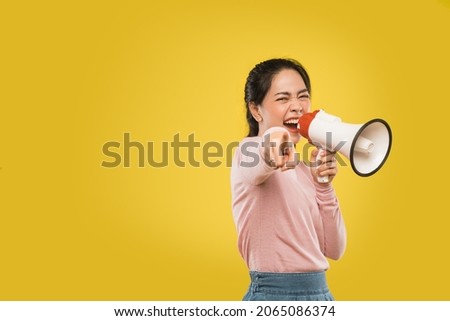 Excited beautiful woman talking seriously holding megaphone and finger pointing
