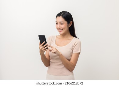 Excited Beautiful young asian woman using smartphone mobile standing on isolated white background. Playing game on smartphone winning victory moment. Very happy enjoy and fun relax time