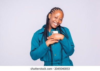 Excited Black African Millennial Women Smiling Holding Her Phone Number O Her Chest After Receiving A Phone Come From He Loved One's 