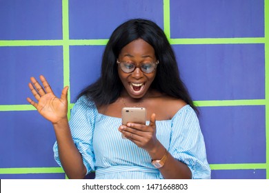 excited Black African woman reading any interesting news on her smartphone 