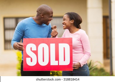 Excited Black Couple Holding Sold Sign Outside Their House