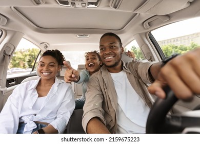 Excited Black Family Driving New Auto, Daughter Pointing Finger Showing Destination Of Road Trip. Parents And Kid Traveling On Vacation By Car Enjoying Ride Outdoors. Selective Focus - Powered by Shutterstock