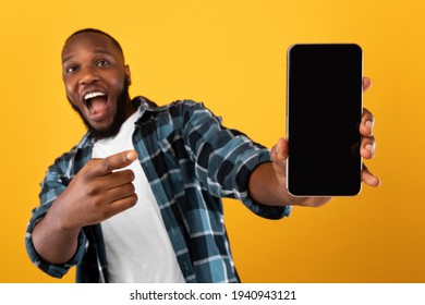 Excited Black Guy Showing Mobile Phone Screen On Yellow Background