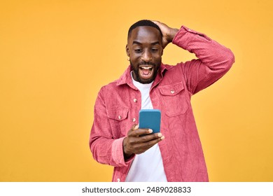 Excited Black man looking at smartphone with wow reaction isolated on yellow. Happy African young gen z guy holding cellphone reading message on cell phone. Amazed user winner using mobile phone - Powered by Shutterstock