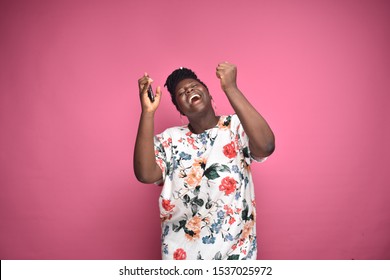 Excited Black Woman, Holding Her Phone, Celebrating By Dancing