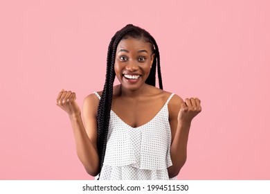 Excited black woman in summer dress gesturing YES on pink studio background. Lovely African American lady celebrating success or achievement, feeling excited and triumphant