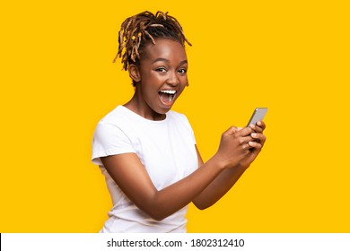 Excited Black Woman Using Mobile Phone Over Yellow Background, Got New Nice App, Copy Space