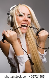 Excited blond model biting headphones cable