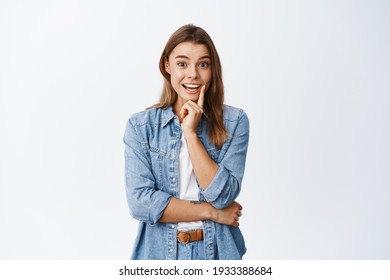 Excited blond woman staring interested and smiling at camera, hear interesting news, listen to big announcement happy, standing against white background - Shutterstock ID 1933388684