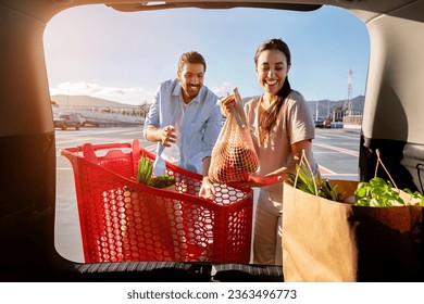 Excited brazilian spouses man and woman packing shopping bags with fresh food into the car trunk, view from the vehicle interior. Young couple loading purchases inside - Powered by Shutterstock