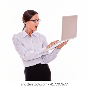 Excited Brunette Businesswoman Using Laptop With Open Mouth In A Gesture Of Surprise While Wearing Her Straight Hair Back And A Button Down Shirt On A White Background