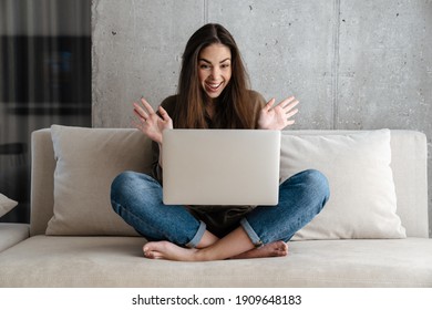 Excited Brunette Nice Girl Expressing Surprise While Using Laptop At Home