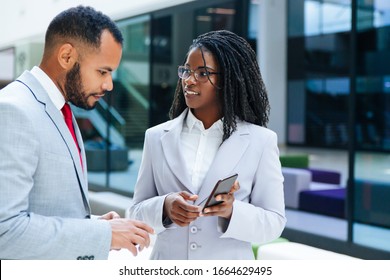 Excited business colleagues watching content on mobile phone together. Business woman showing smartphone screen to male colleague. Media content concept - Shutterstock ID 1664629495