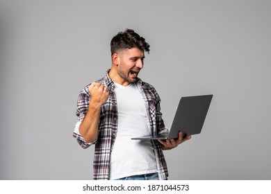 Excited Business Man Looking At Laptop Screen With Mouth Wide Open, Celebrating His Win On Gray Background