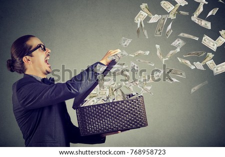 Excited business man opening an box letting dollar banknotes to fly away 