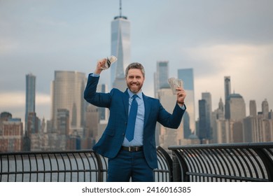Excited Businessman hold dollar banknote over New York City. Dollar notes concept. Credit and loan in USA. American finance. Businessman hold hundred dollar banknotes outdoor. Celebrating the success.
