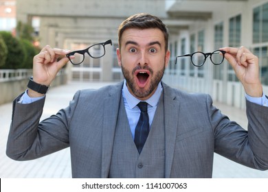 Excited businessman holding two pair of eyeglasses 