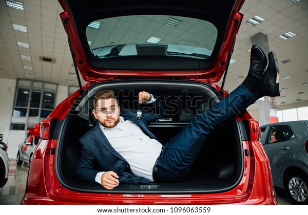Excited
businessman sitting in car. Showing new car
key.