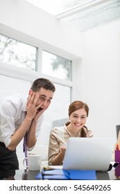 Excited businessman and woman in office, looking at laptop - Shutterstock ID 545649265