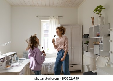 Excited Caucasian Mother And Teenage Daughter Have Fun Sign Listen To Music On Weekend At Home Together. Happy Mom And Teen Child Feel Crazy Dance Jump, Enjoy Leisure Family Entertainment Time.