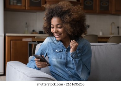 Excited cheerful gen Z African teenager girl using mobile phone, getting surprising good news, looking at screen, laughing, celebrating win, success, luck, achieve, good result - Shutterstock ID 2161635255