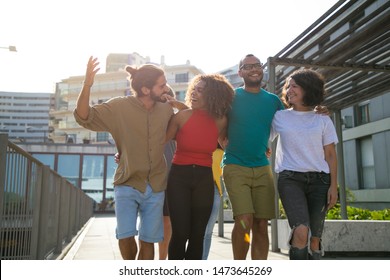 Excited Cheerful Mix Raced Friends Enjoying Walking Outdoors. Multiethnic Group Of People Walking Outside, Hugging Each Other, Talking And Laughing. Multicultural Friendship Concept