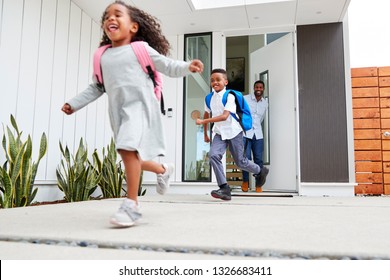 Excited Children Running Out Of Front Door On Way To School Watched By Father