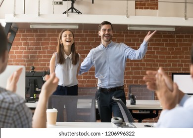 Excited company boss or team leader introducing new employee to colleagues in office welcoming hired newcomer member congratulating with promotion applauding celebrating reward, supporting coworker - Powered by Shutterstock