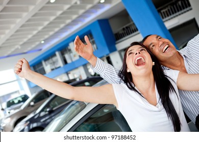 Excited Couple Buying A Car At The Dealer With Arms Up