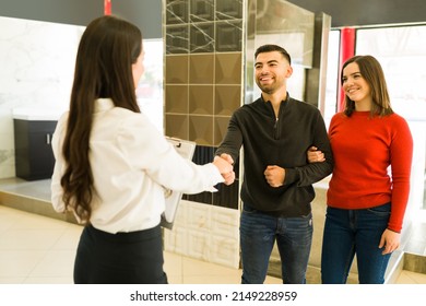 Excited Couple Of Customers Smiling And Shaking Hands With A Salesperson After Buying Furniture At The Store