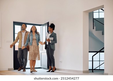 Excited couple entering in a new house while meeting with their real estate agent. Copy space. - Powered by Shutterstock