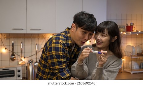 Excited Couple Looking At Pregnancy Test Result At Home And Hugging Each Other With Joy After Finding They Are Going To Have A Baby