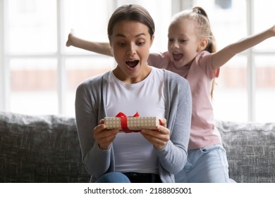 Excited Daughter Girl Giving Birthday Gift Box To Amazed Mum. Happy Surprised Mommy Receiving Present Wrap From Preschooler Kid. Family Celebrating Mothers Day. Congratulation, Special Date Concept