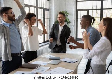 Excited Diverse Employees Celebrating Great Teamwork Result At Meeting, Sharing Success, Business Achievement, Happy Colleagues Laughing, Rejoicing Victory, Standing In Modern Office Together