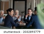 Excited diverse employees eating pizza during break in office together, happy Indian businesswoman laughing at funny joke, talking chatting with colleagues, having fun, sharing corporate lunch