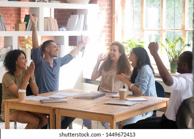 Excited Diverse Students Or Employees Celebrating Success, Business Achievement, Good Exam Result At Meeting, Happy African American And Asian Team Members Having Fun Together In Classroom Or Office