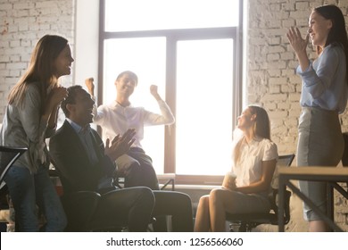 Excited diverse team people applauding celebrating success supporting leader telling great news, happy multi-ethnic employees sales group congratulating colleague with business achievement or reward
