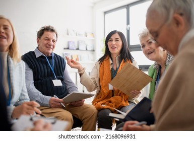 Excited elderly people attending group therapy session at nursing house, positive senior man and woman sitting in circle, having conversation with psychologist - Powered by Shutterstock