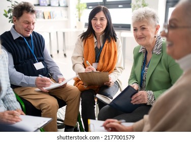 Excited Elderly People Attending Group Therapy Session At Nursing House, Positive Senior Man And Woman Sitting In Circle, Having Conversation With Psychologist