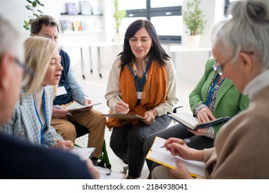 Excited Elderly People Attending Group Therapy Session At Nursing House, Positive Senior Man And Woman Sitting In Circle, Having Conversation With Psychologist