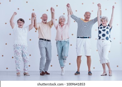 Excited elders holding hands in the air and welcoming new year together - Powered by Shutterstock