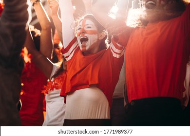 Excited England soccer fans celebrating in stands. English football supporters cheering over a goal in stadium.
