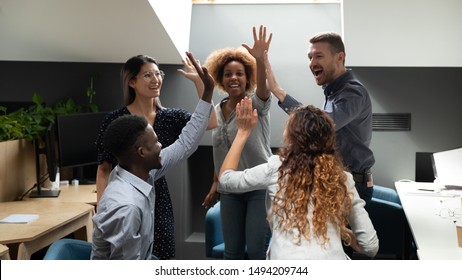 Excited euphoric multiracial business team give high five in office celebrate company growth, corporate success, help in goal achievement, good teamwork result, teambuilding partnership power concept
