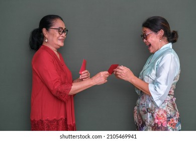 Excited Expression Of A Woman Receiving Red Envelope From Another Woman.