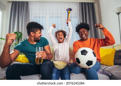 Excited Family Watching Football Match At Home