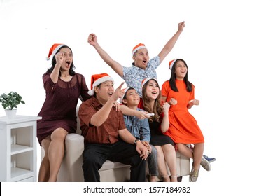 Excited Family Watching Tv Together Wearing Christmas Head