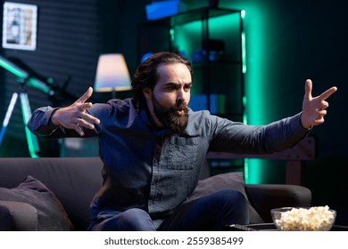 Excited fan watching live sports event on TV, whistling and chanting for team. Supporter at home doing energetic hand gesturing, cheering for own club to triumph in competition - Powered by Shutterstock