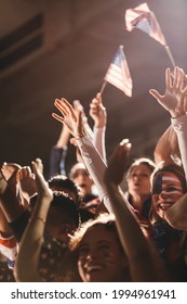 Excited Fans With US Flag In Sports Crowd, Celebrating And Cheering On Team Success. Group Of American Soccer Fans Celebrating Victory.