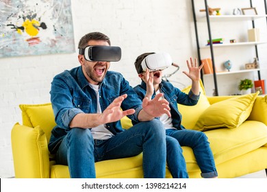 excited father and son in vr headsets experiencing Virtual reality on couch at home - Powered by Shutterstock